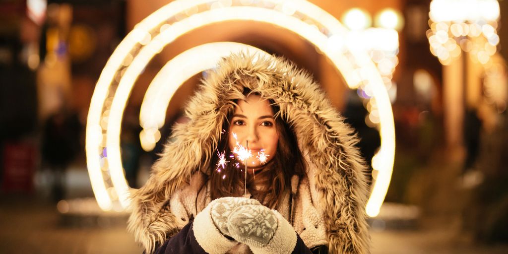 woman wearing coat and holding fireworks