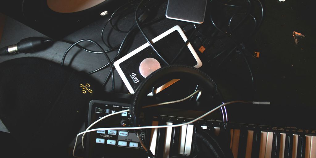 flat-lay photo of headphones, MIDI keyboard, and speaker on black surface