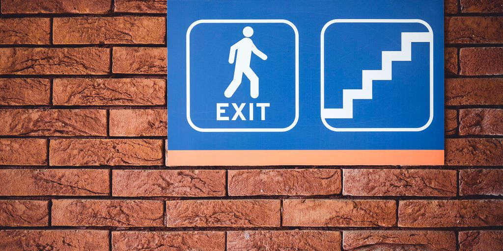 blue and white exit signage mounted on brown brick wall